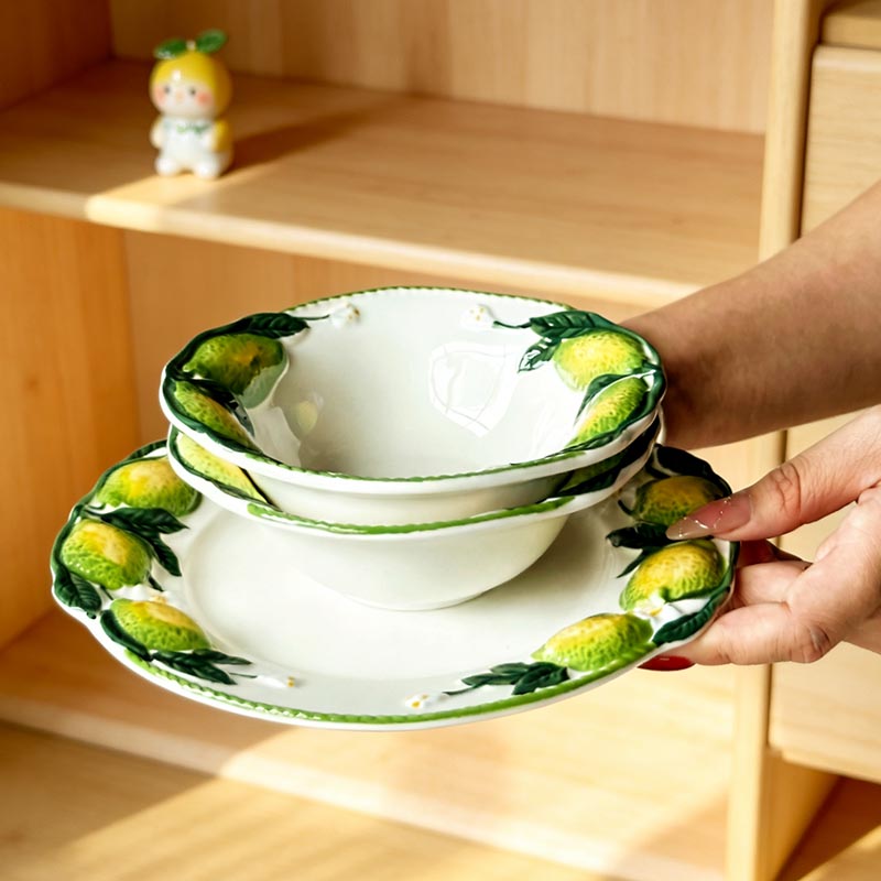 Hand-painted lemon ceramic bowl and plate held by hand - Form Feast
